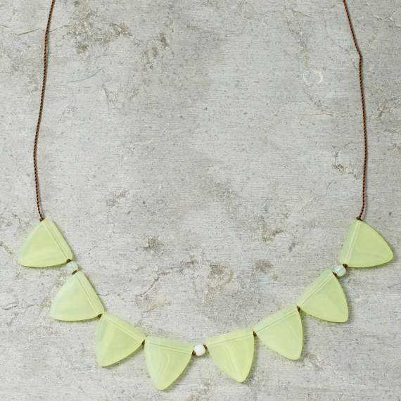 Necklace with light green triangular pendants on a gray surface