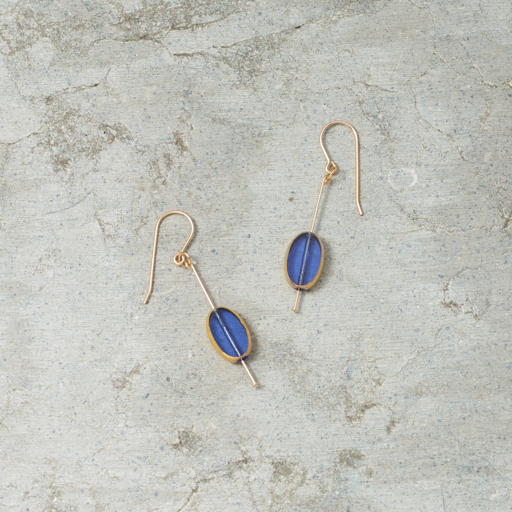 Pair of gold earrings with blue stones on a textured gray surface