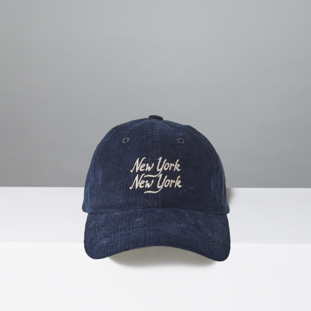 Navy blue corduroy cap with 'New York New York' text on a gray background
