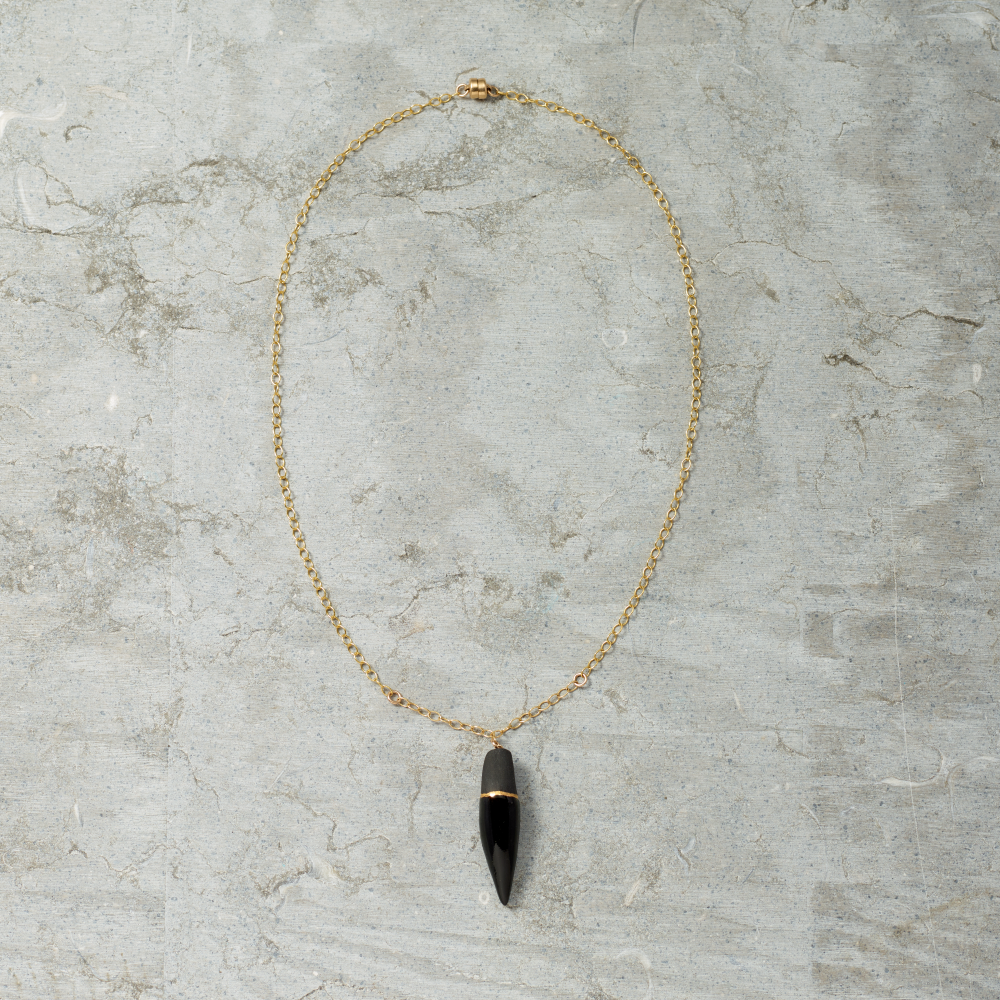 Necklace with a black and gold pendant on a gray marble surface