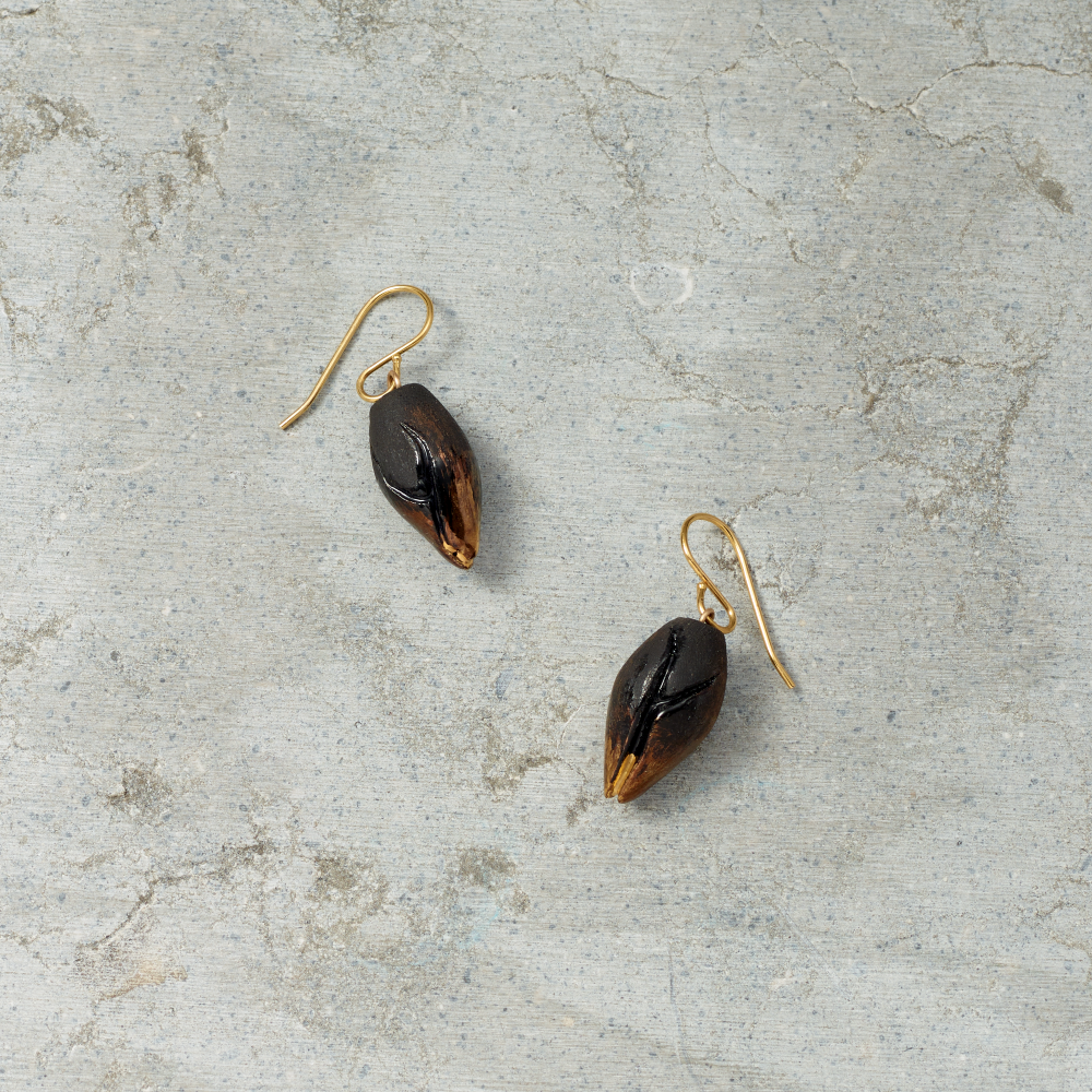 Pair of gold and black earrings on a textured gray surface