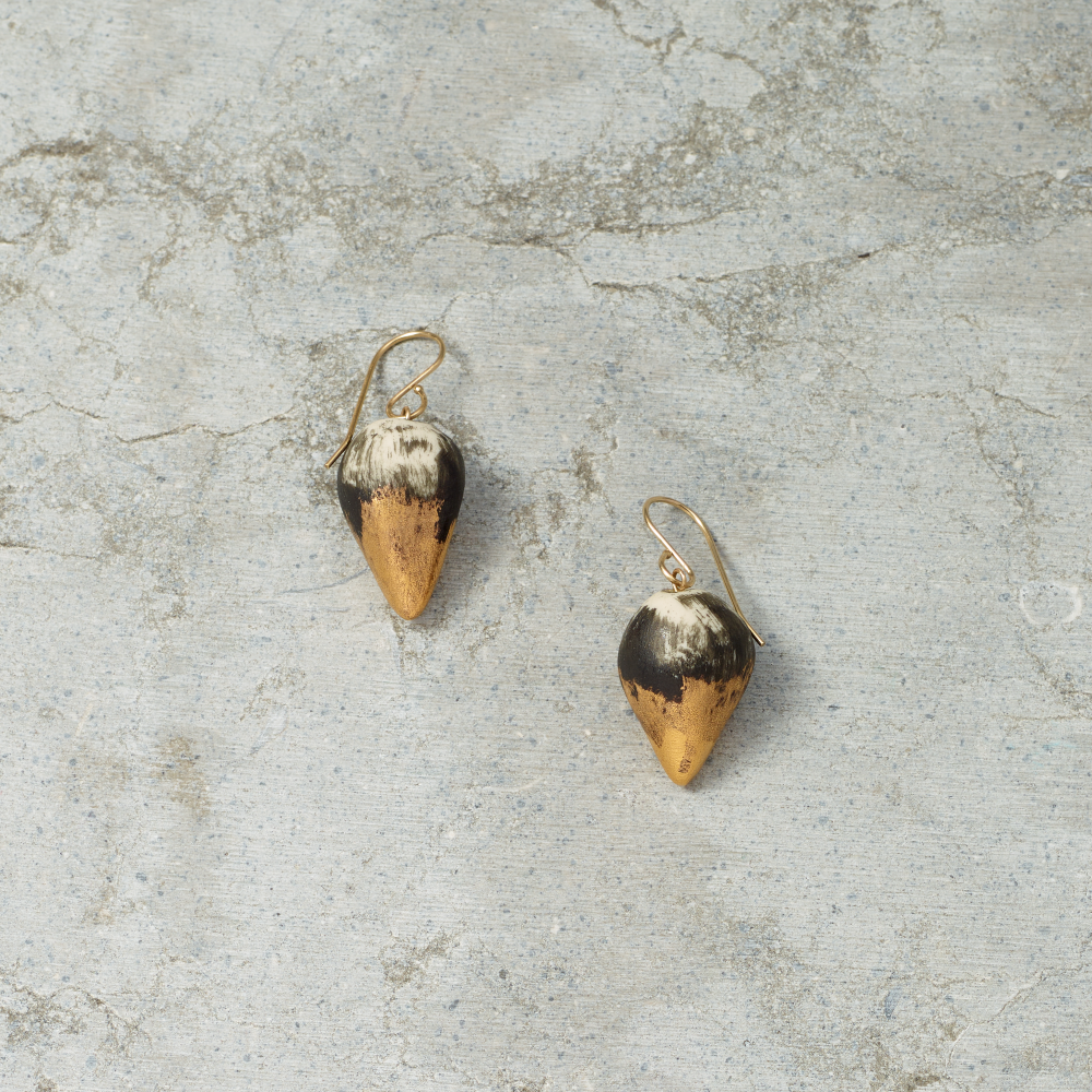 Pair of gold and black earrings on a textured gray surface