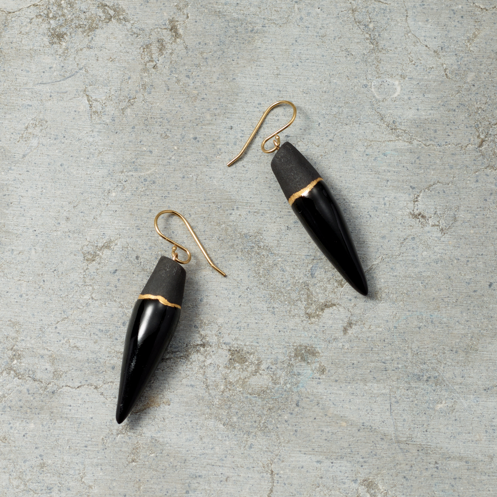 Black and gold earrings on a textured gray surface