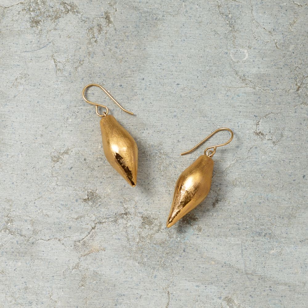 Gold earrings on a textured gray surface