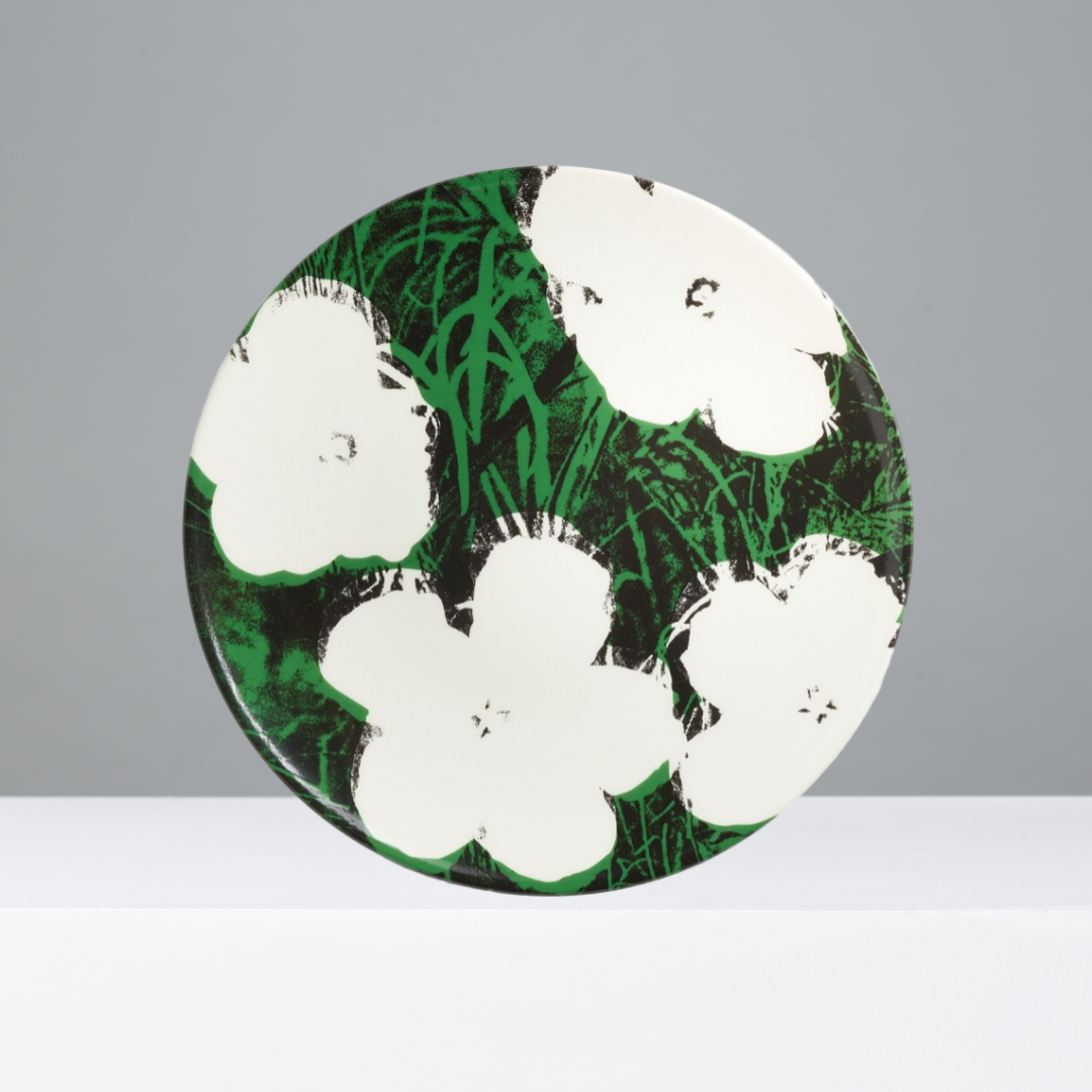 Round green and black patterned plate with white flowers on a gray background