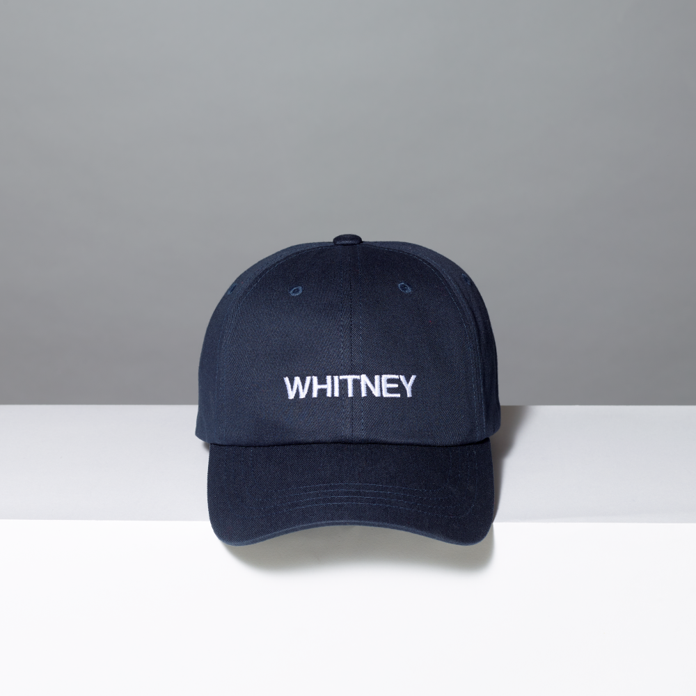 Navy blue cap with 'WHITNEY' logo on a gray and white background