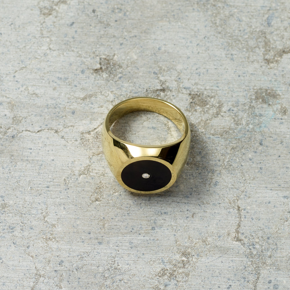Gold ring with a black center on a textured gray surface