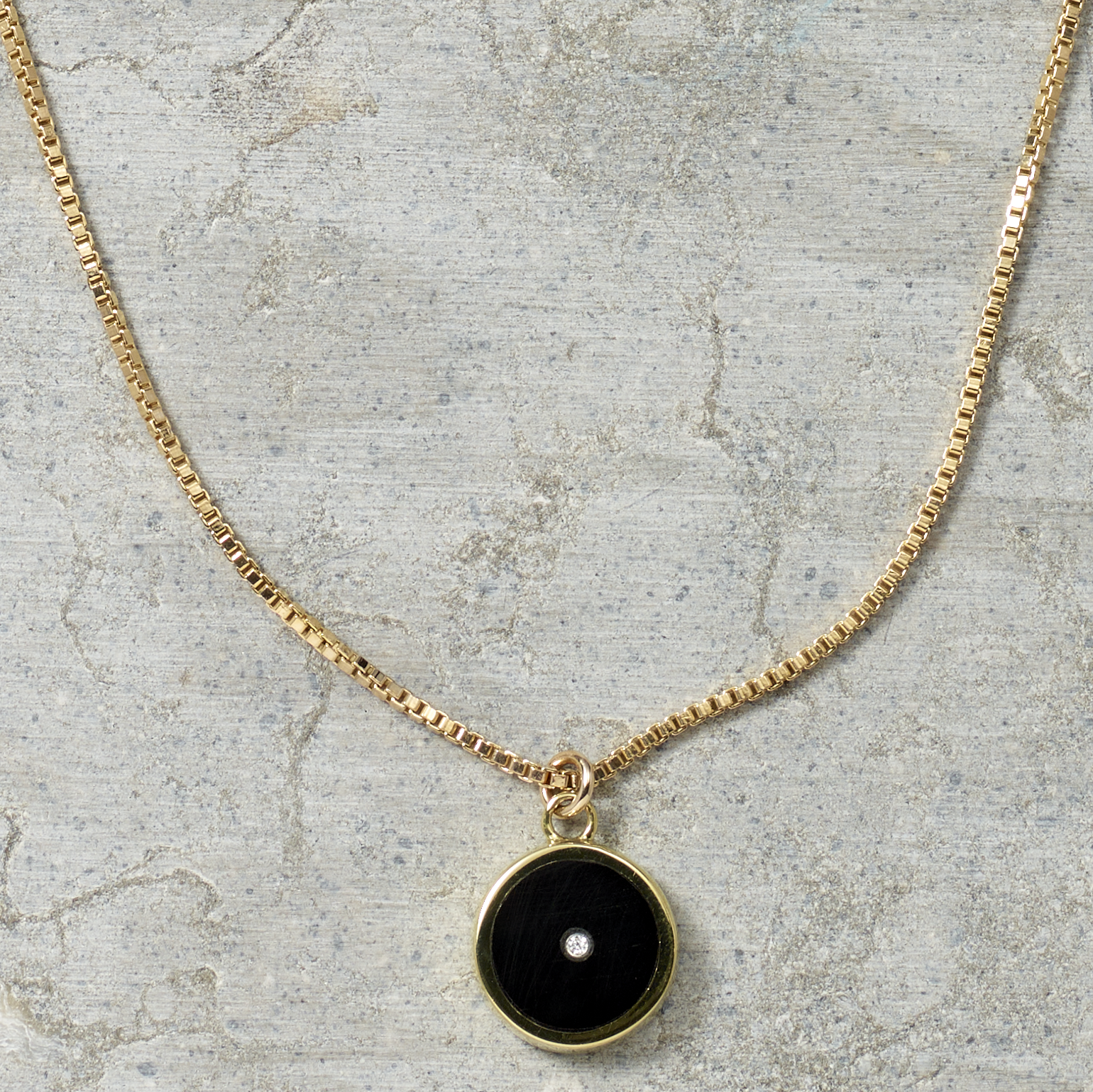 Necklace with a black pendant on a textured surface