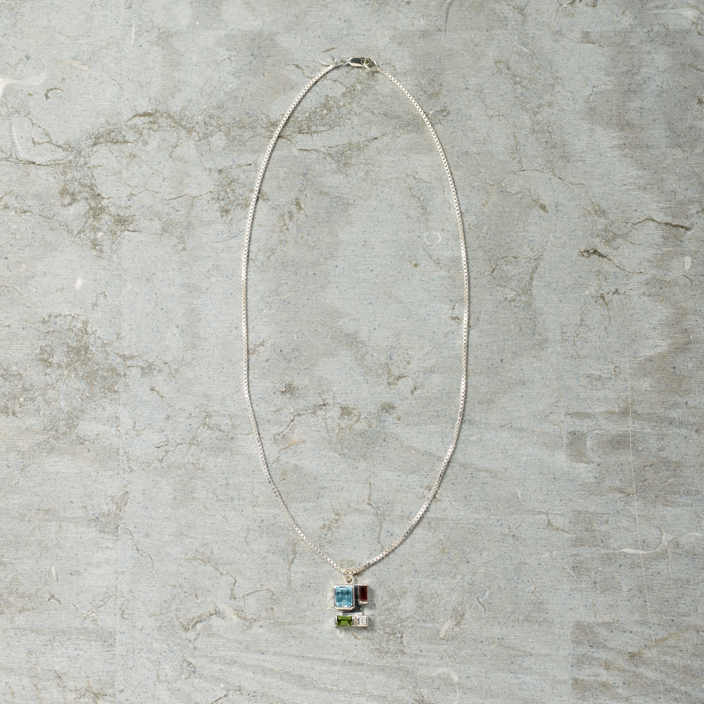 Silver necklace with a pendant on a gray marble surface