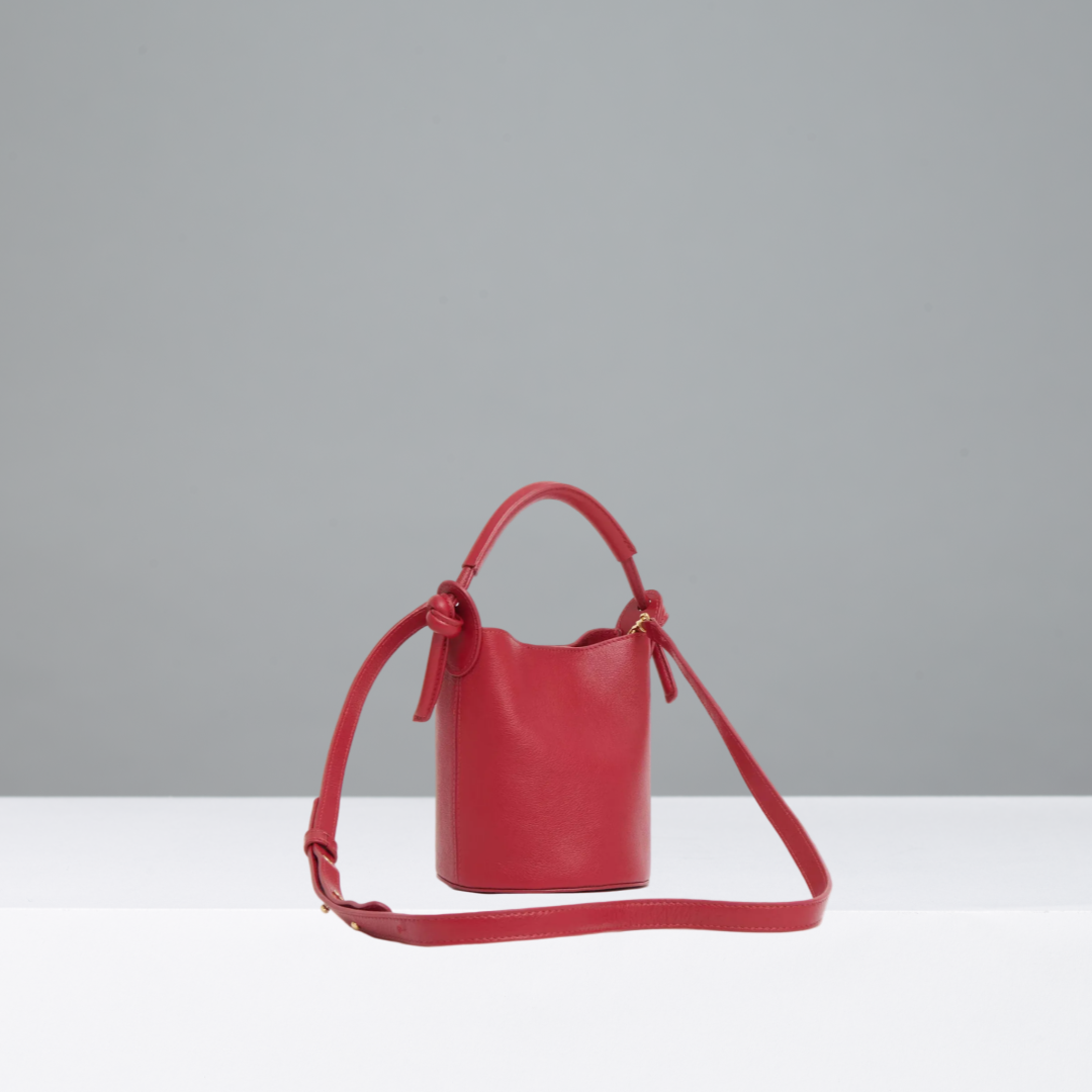 Red handbag with a strap on a gray background