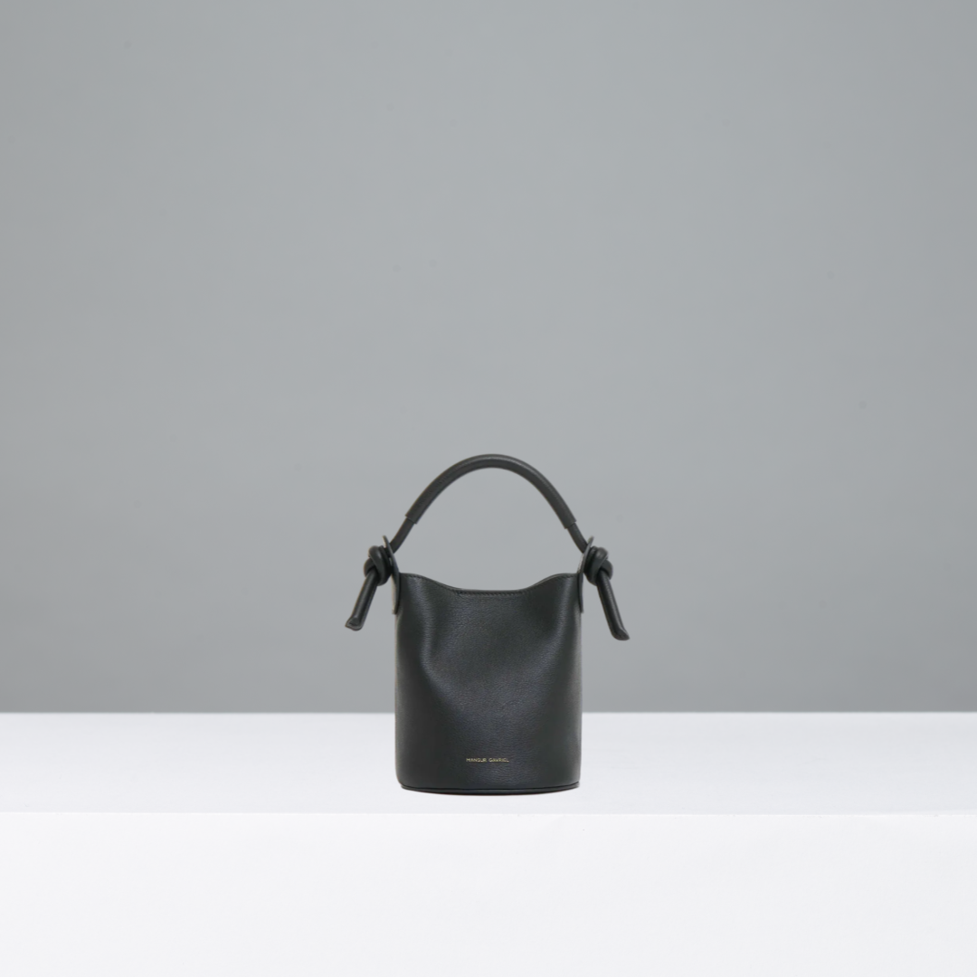Black handbag with a knot detail on a gray background