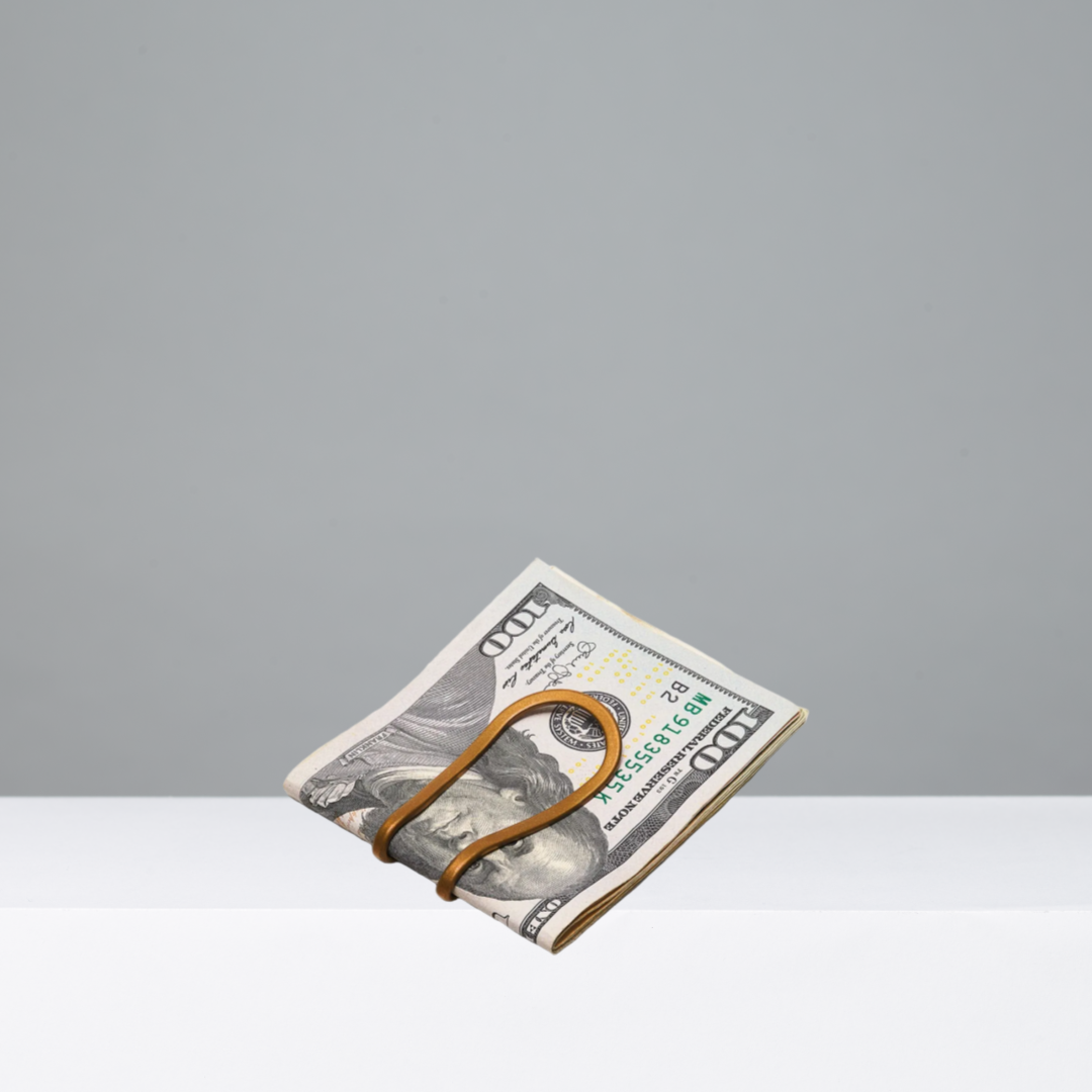 Folded bill with a gold money clip on a gray background
