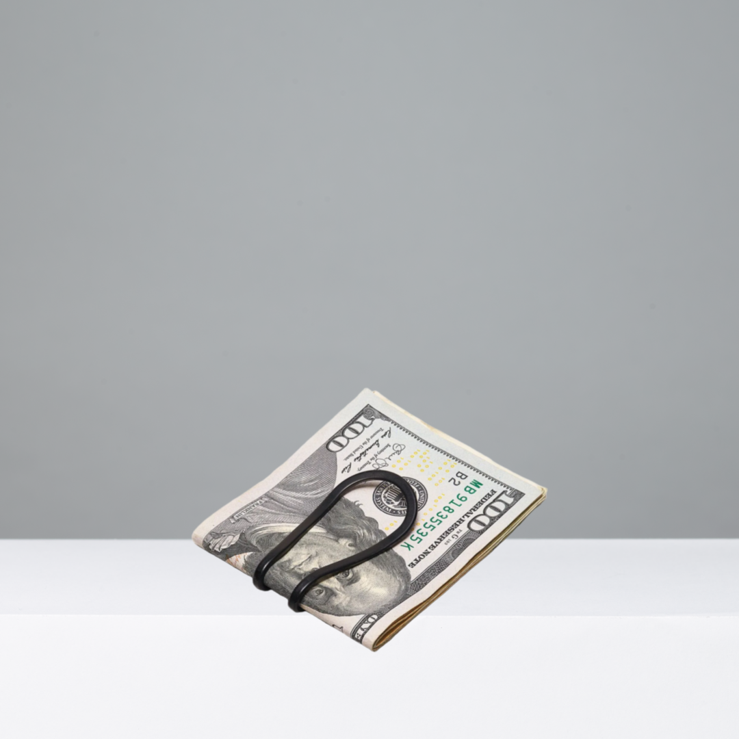 Folded bill with a black money clip on a gray background