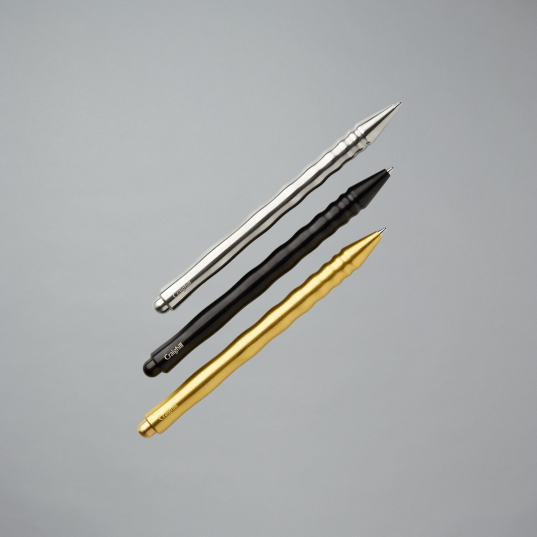Three pens in gold, black, and silver on a gray background