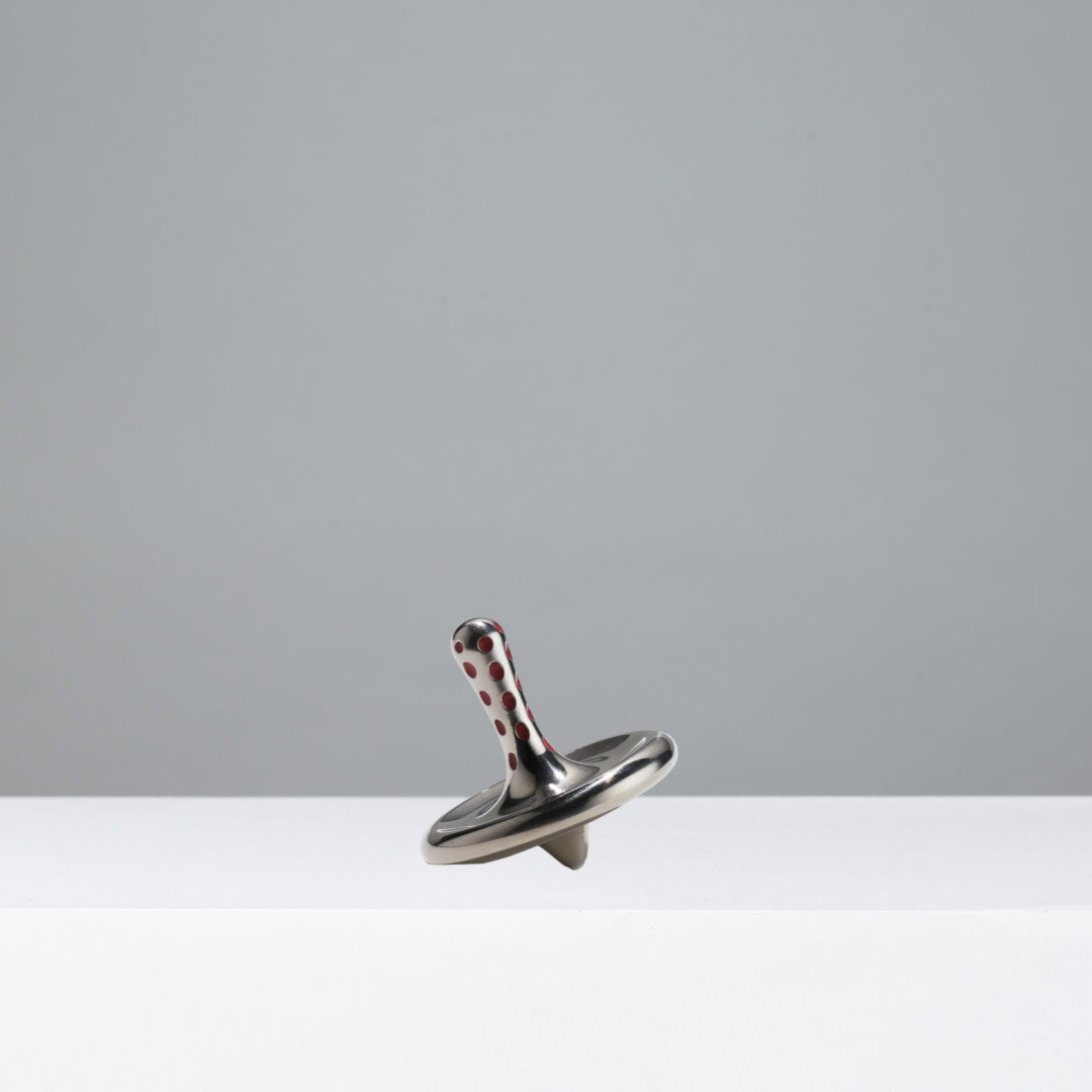 Metallic spinning top on a gray background