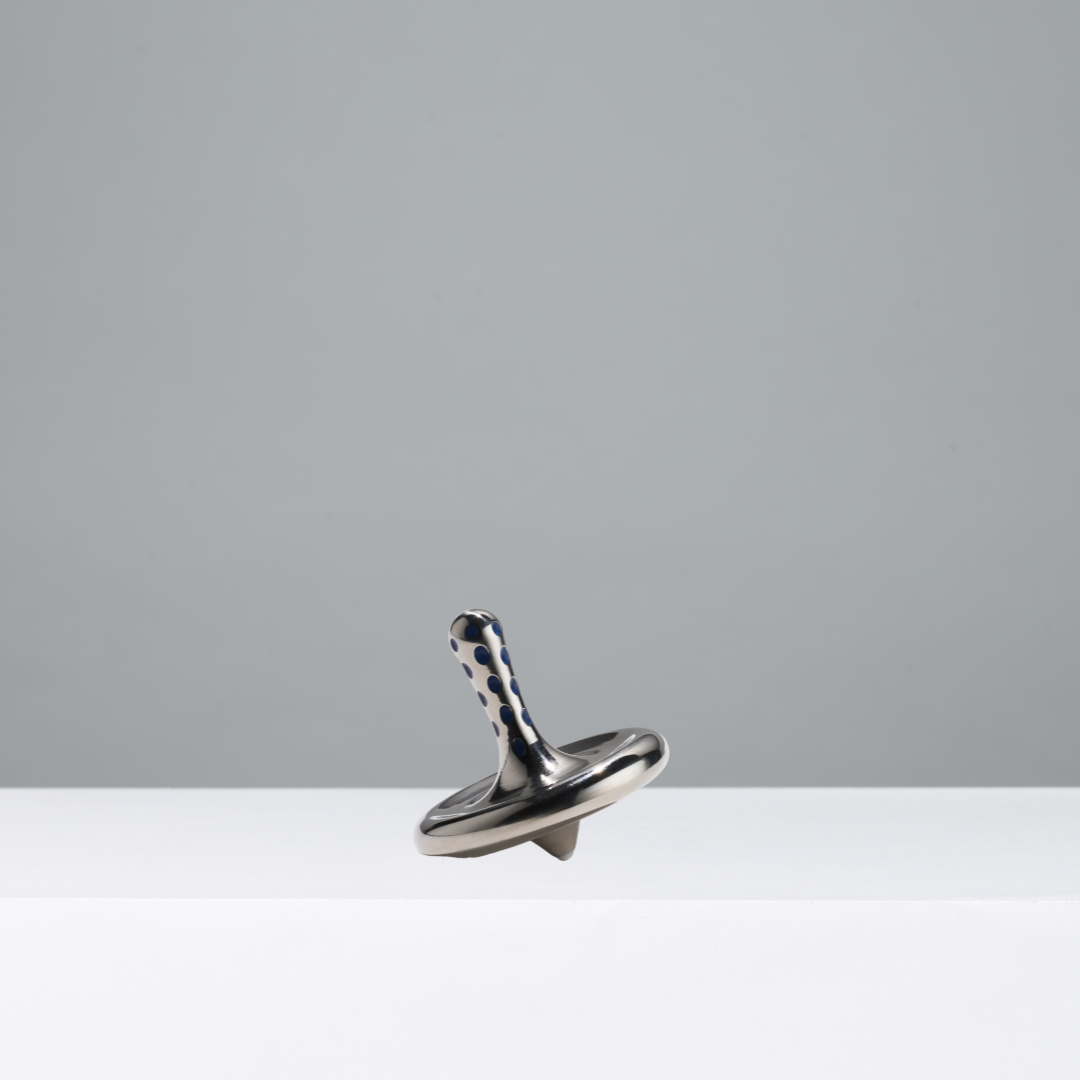 Metallic spinning top on a white surface with a gray background
