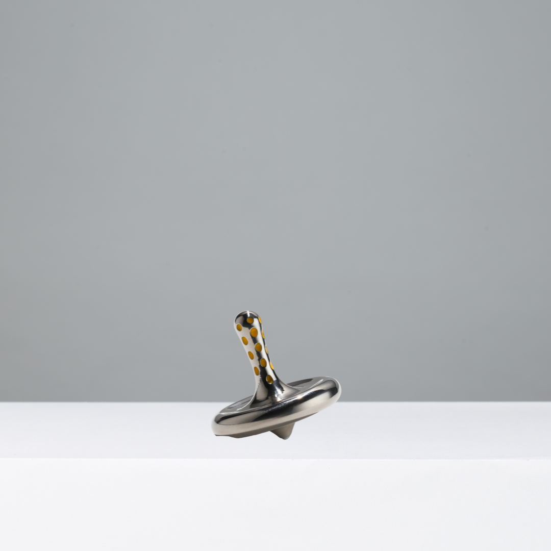 Metallic spinning top on a gray background