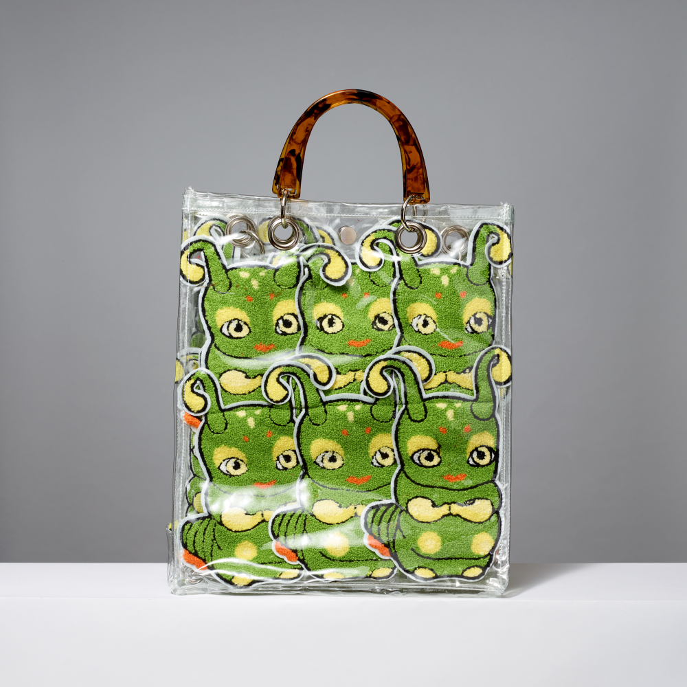 Vinyl tote bag with green caterpillar patches on a gray background