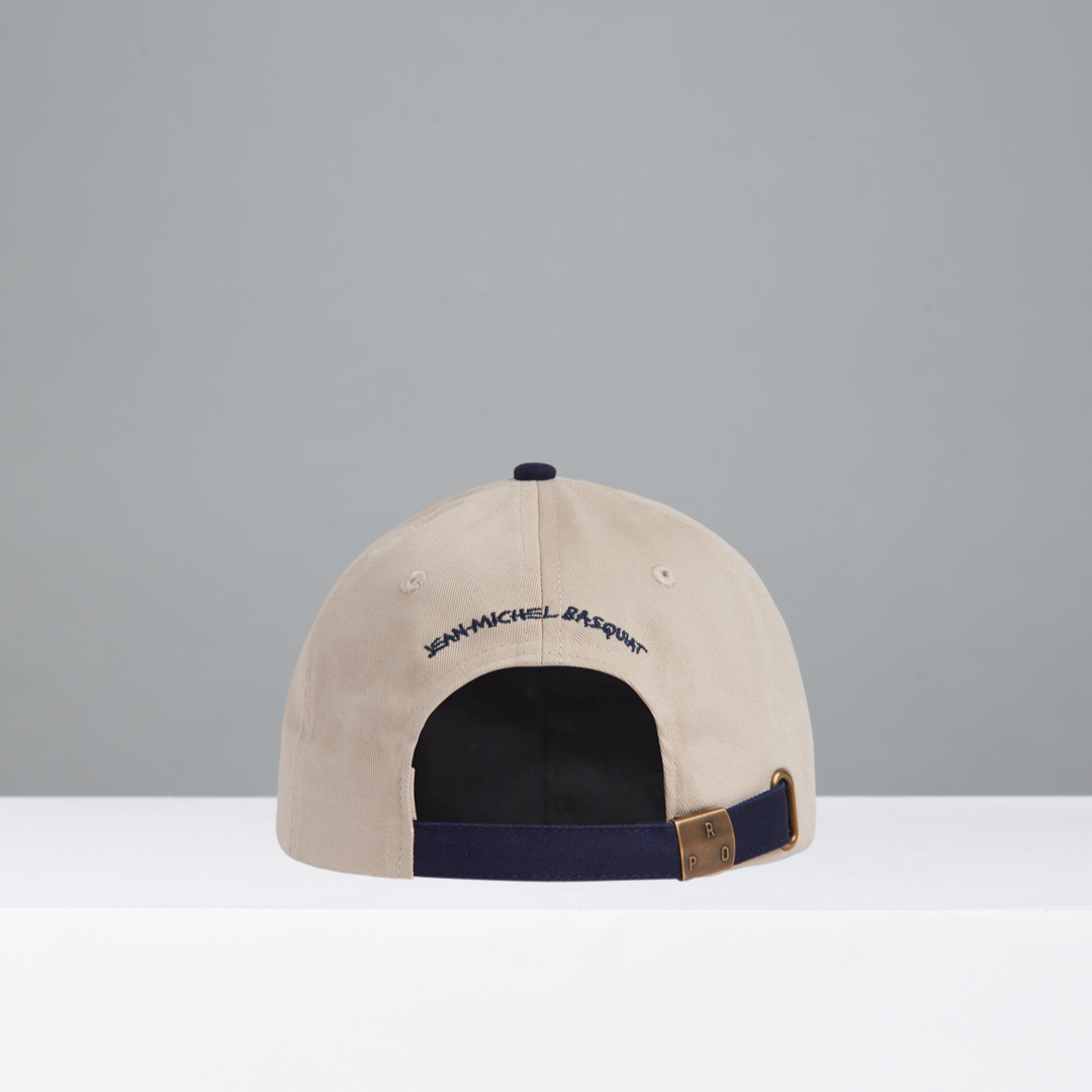 Beige and navy cap featuring Jean-Michel Basquiat in blue embroidery