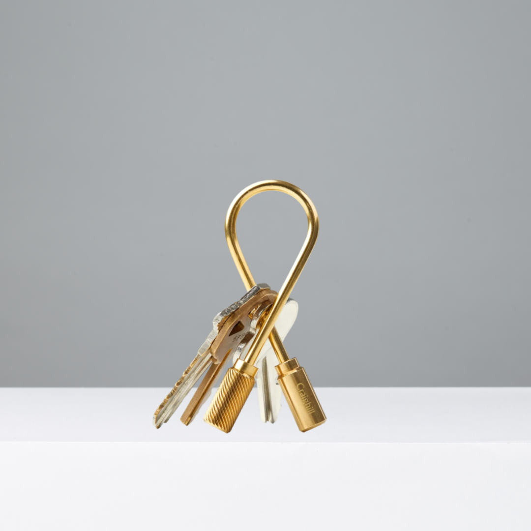 Brass Closed Helix Keyring with keys on a gray background