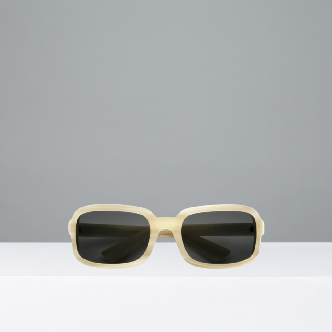 Sunglasses with beige frame and dark lenses on a gray background