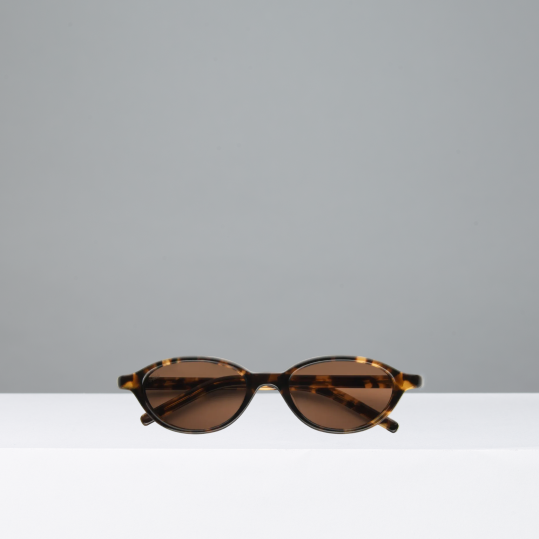 Sunglasses with tortoiseshell frame and brown lenses on a light gray background