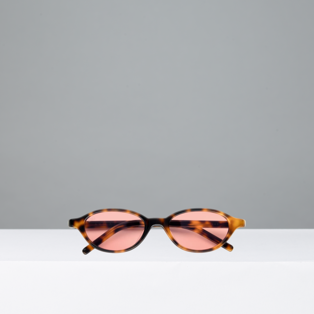 Sunglasses with tortoiseshell frame and pink lenses on a gray background