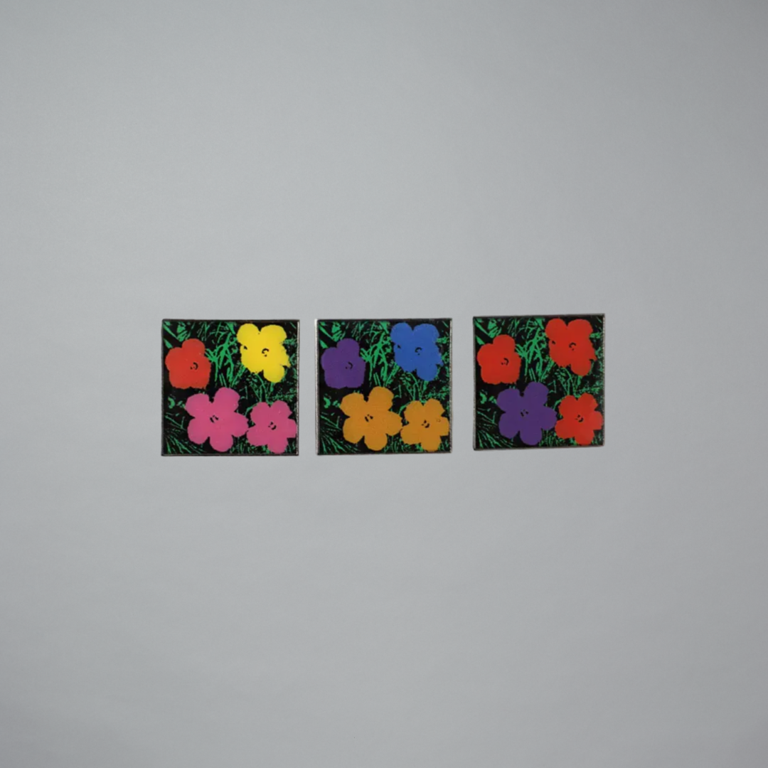 Three square enamel pins with colorful flowers on a gray background
