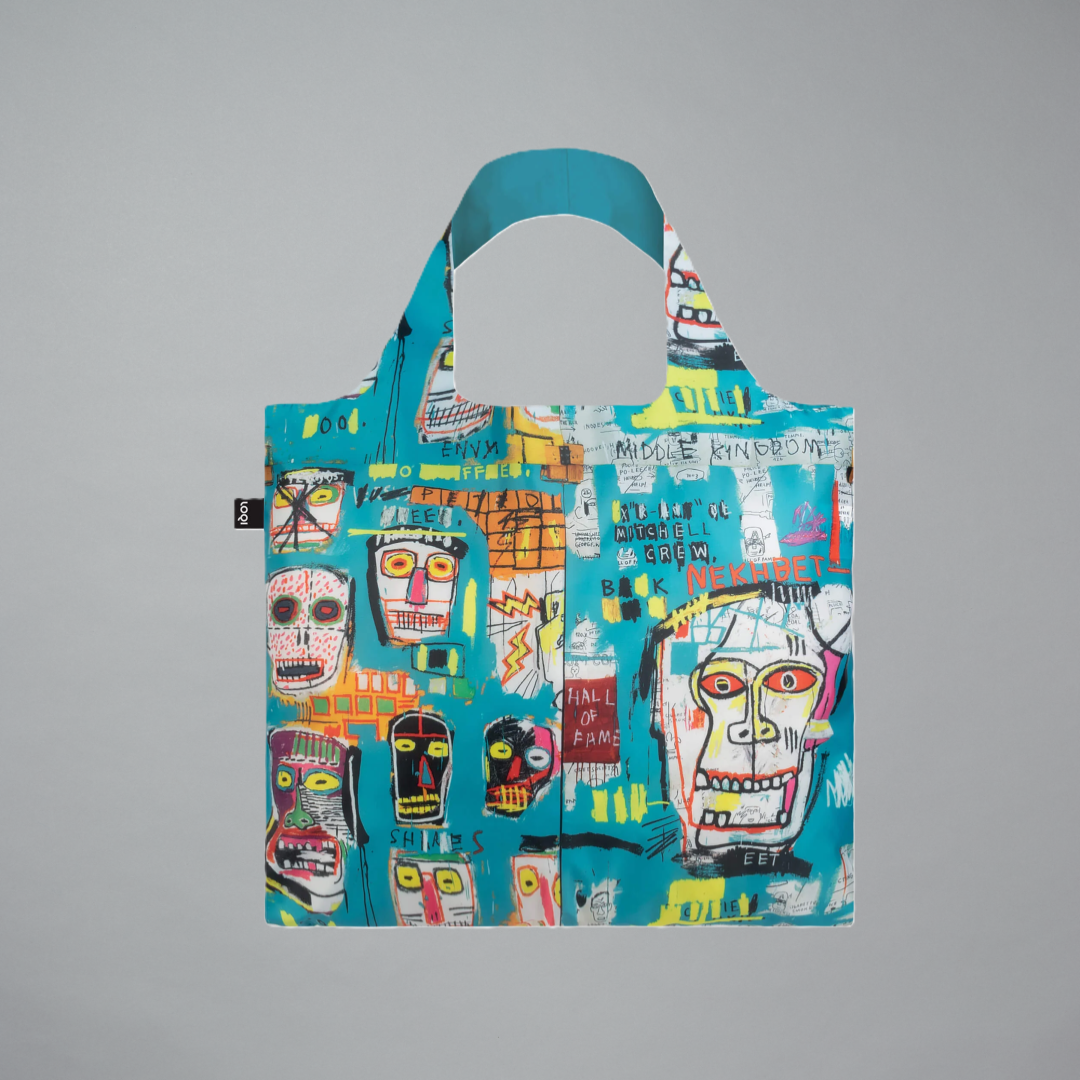 A turquoise reusable tote bag with an all-over graffiti-style multicolor print by Jean-Michel Basquiat on a gray background