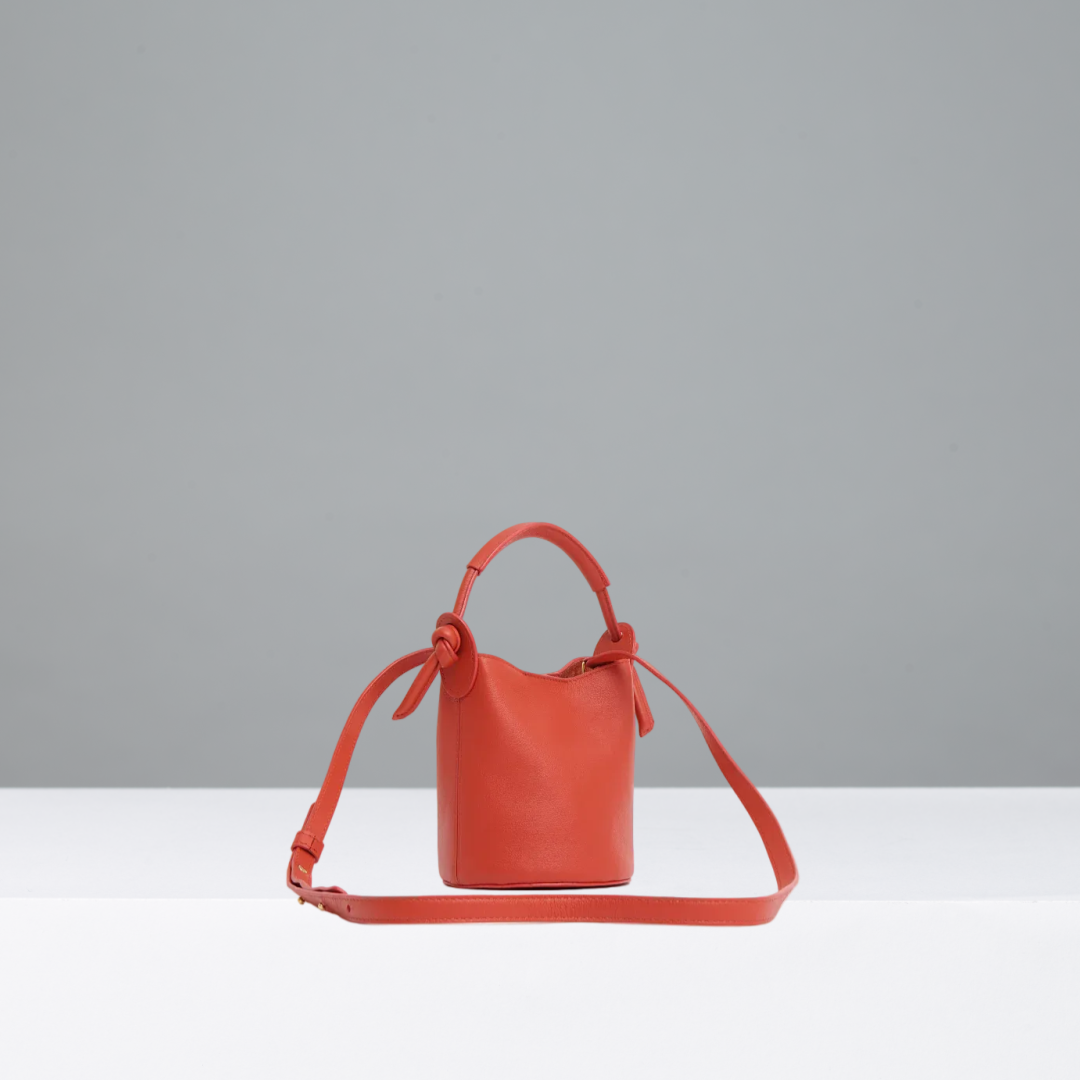 Orange/red bucket bag on a gray background