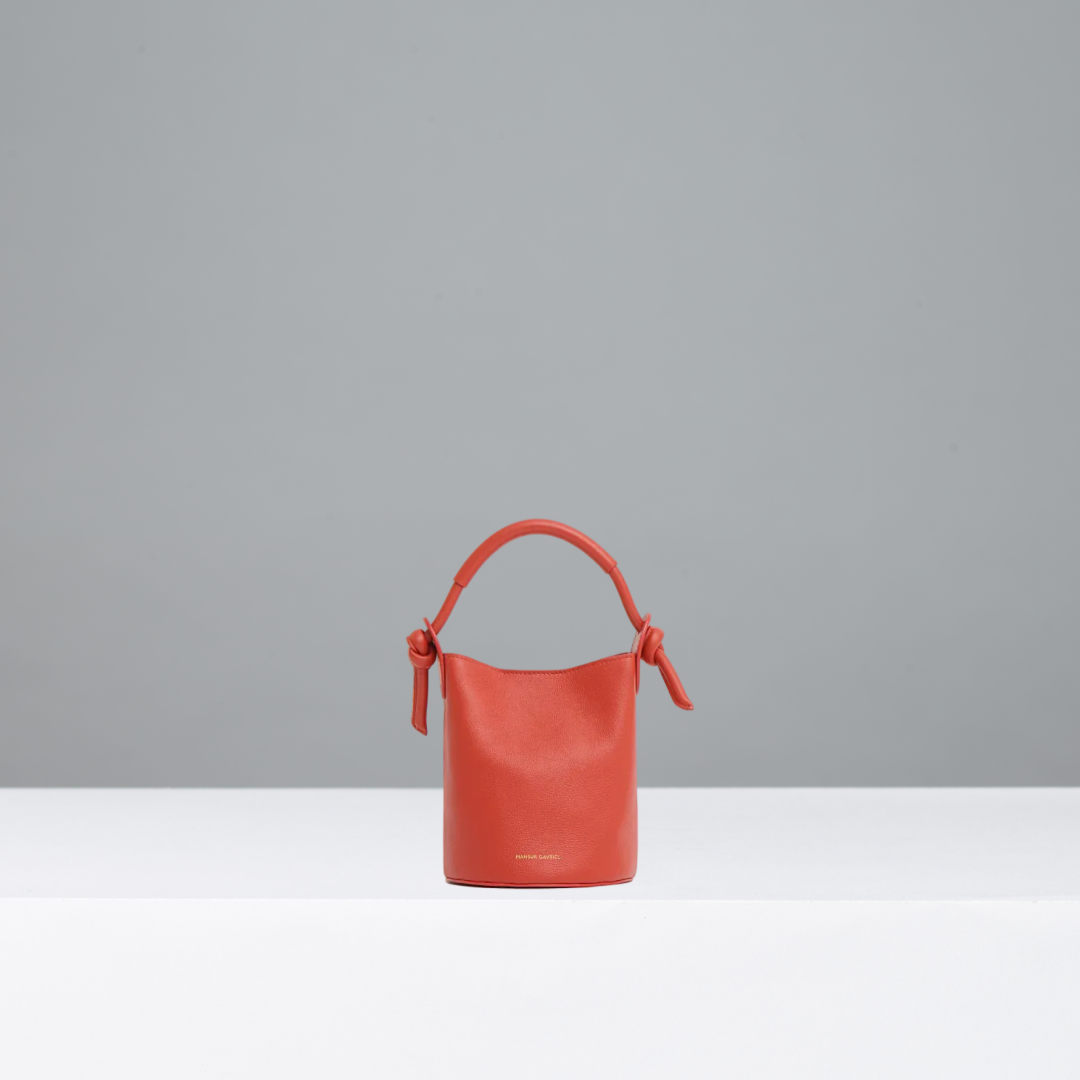 Orange/red bucket bag on a gray background
