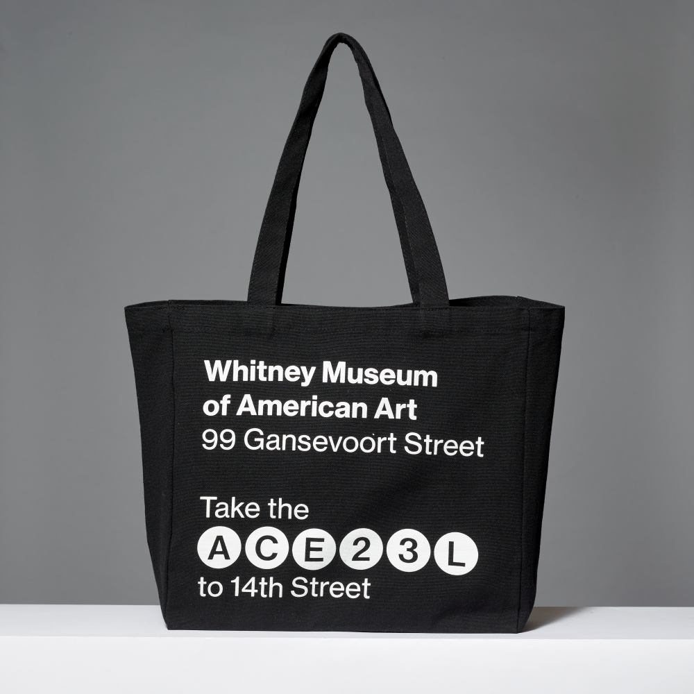 Black cotton tote bag with Whitney Museum of American Art, the address and subway lines screen printed in white on a gray background