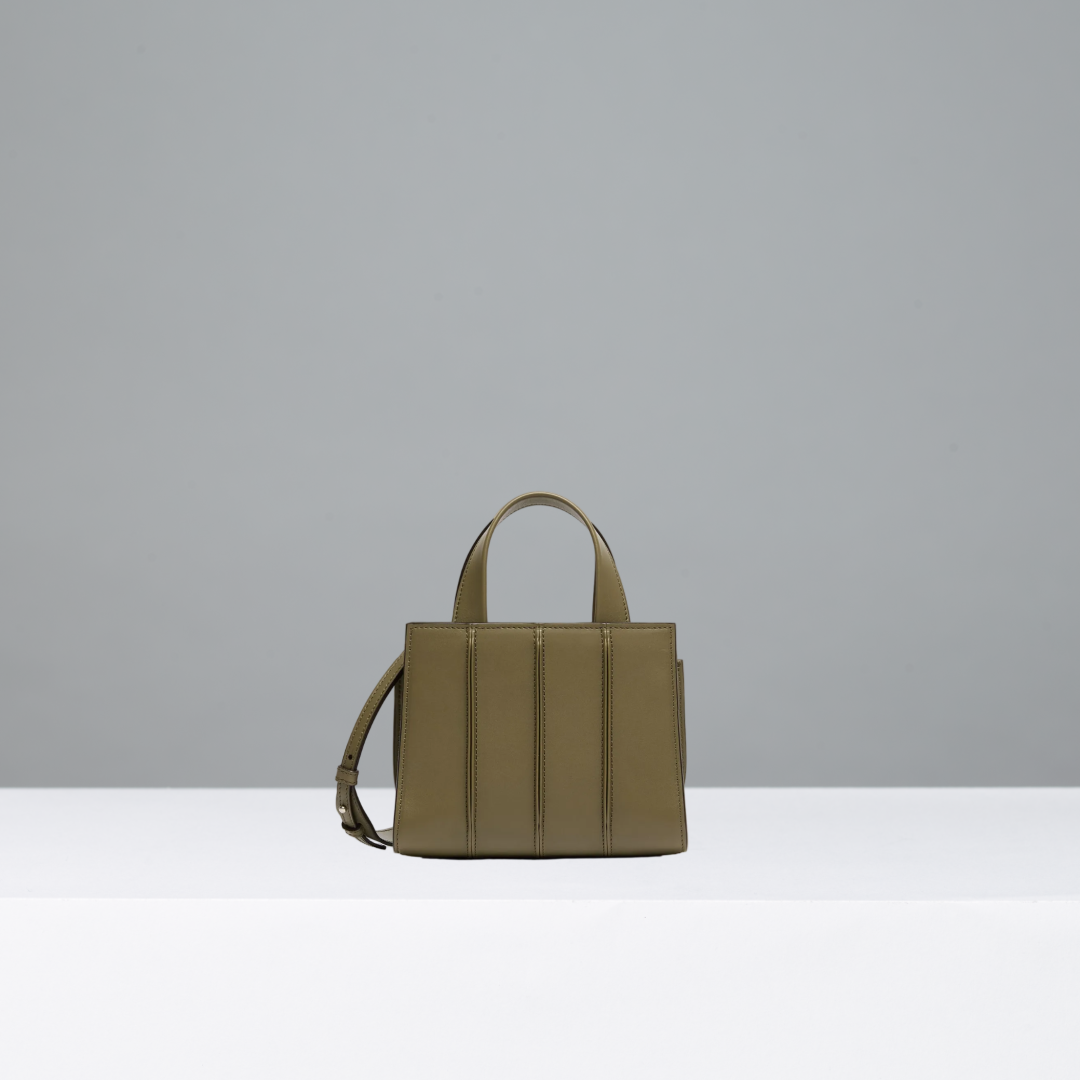 An olive green leather handbag with top handles and a shoulder strap, standing on a white platform against a light gray background.