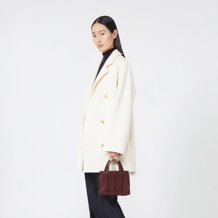 Model holding a red handbag on a gray background
