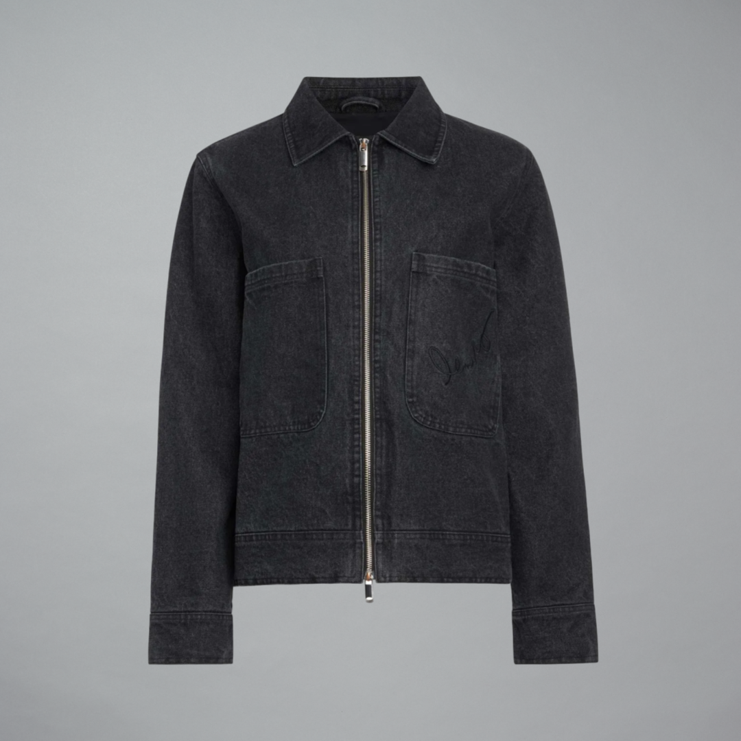 A dark denim black zip-up jacket with a pointed collar, two front flap pockets, and a silver-tone zipper, shown against a solid gray background