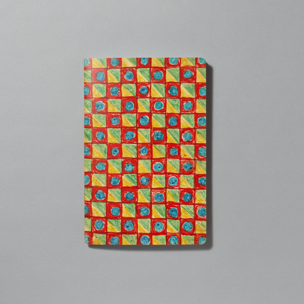 A rectangular notebook with a detail of Minnie Evans's Checkered Design consisting of a colorful geometric pattern of red, yellow, green, and blue squares, photographed flat against a neutral gray background.