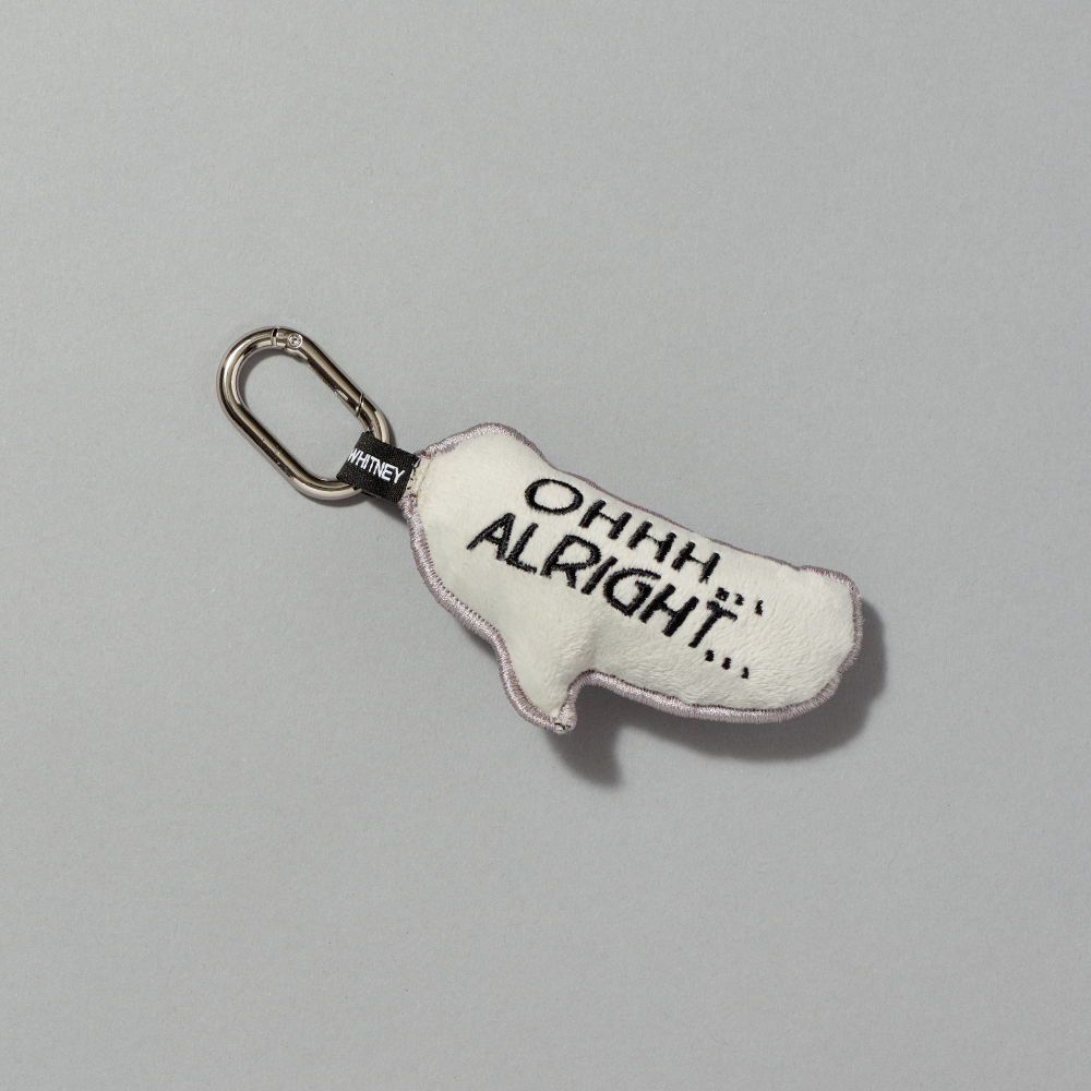 A small off-white plush keychain charm shaped like a quote bubble, featuring the text Ohhh... Alright... inspired by Roy Lichtenstein's work of the same name