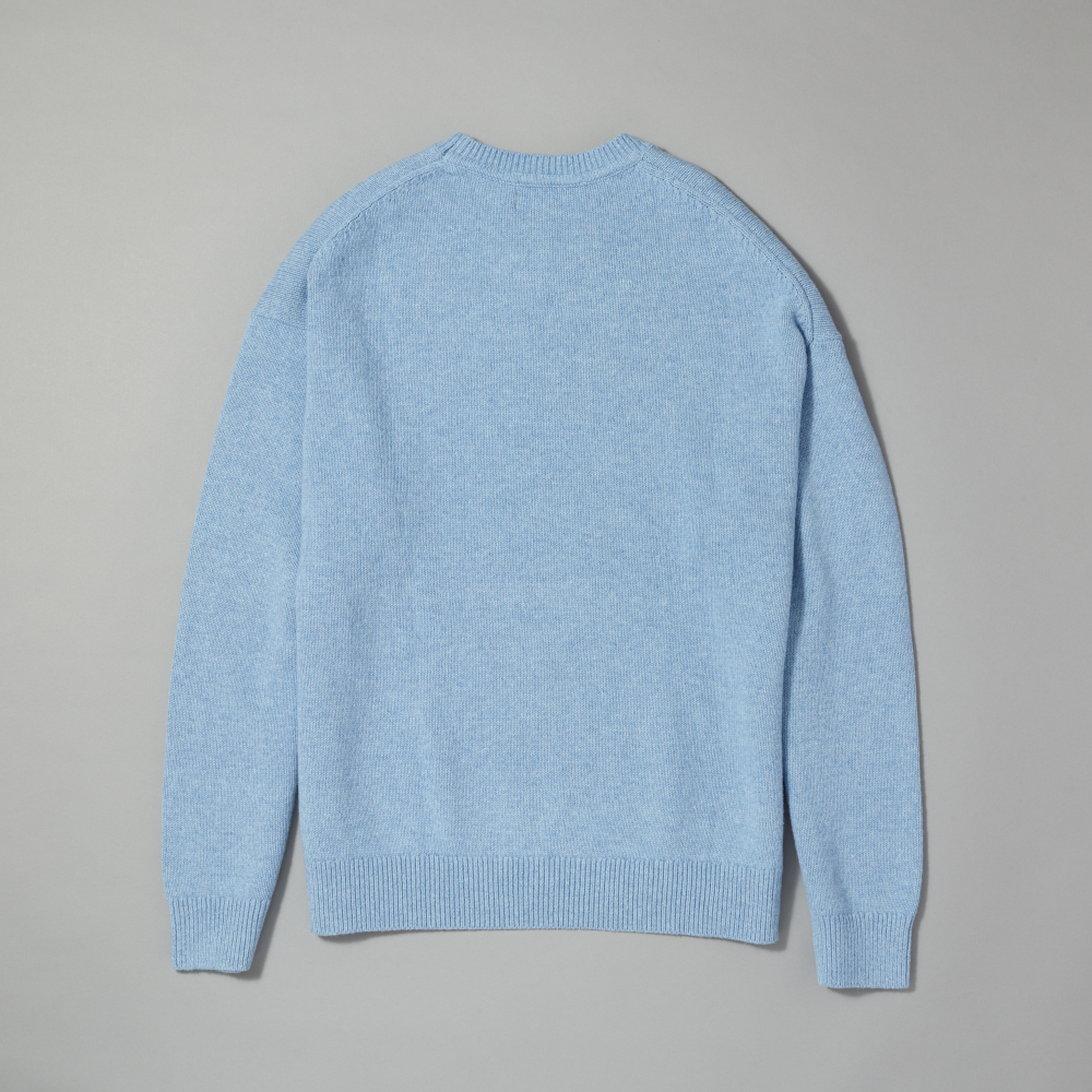 A light blue knit sweater shown from the back, laid flat on a neutral gray background