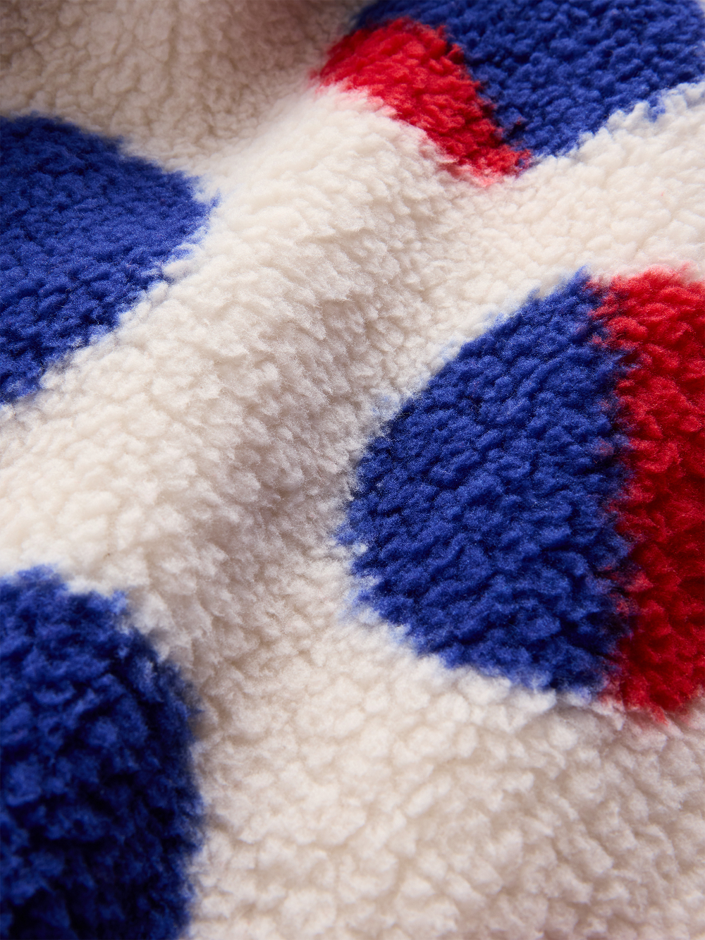 Close-up of a plush sherpa fleece jacket with a bold red and blue polka dot pattern inspired by Roy Lichtenstein's work Cathedral #2