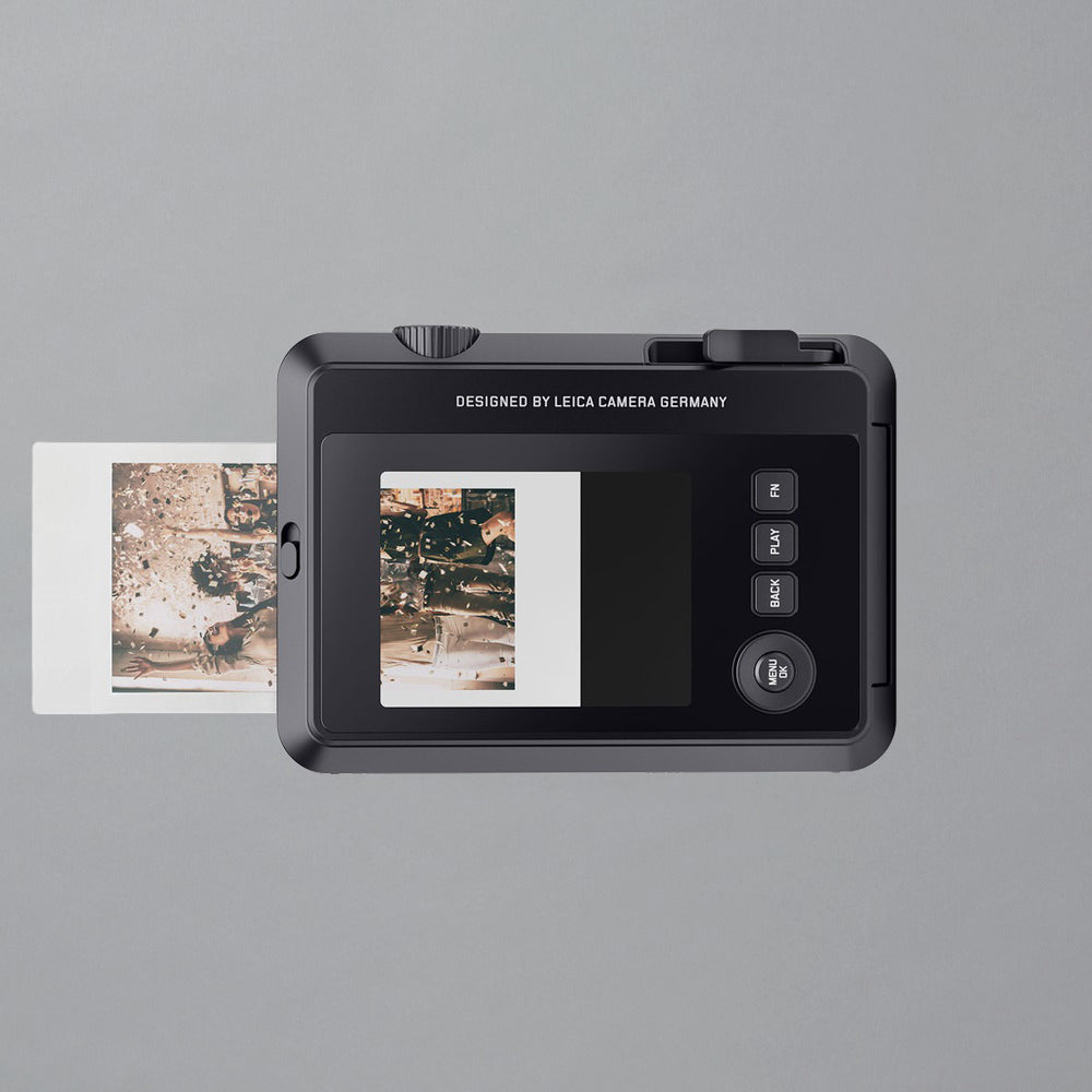 Black digital camera displaying prints on a gray background