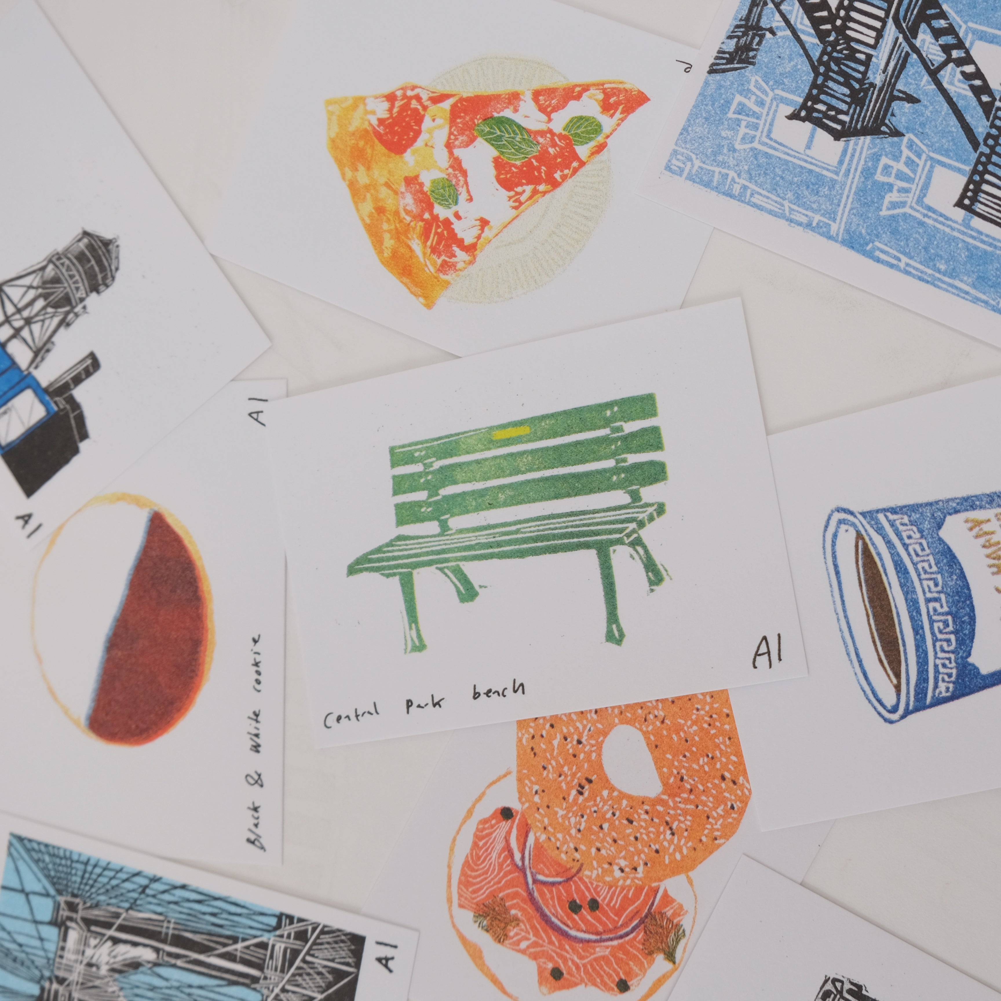 Collection of illustrated prints with various images including a slice of pizza, a bench, and a coffee cup.