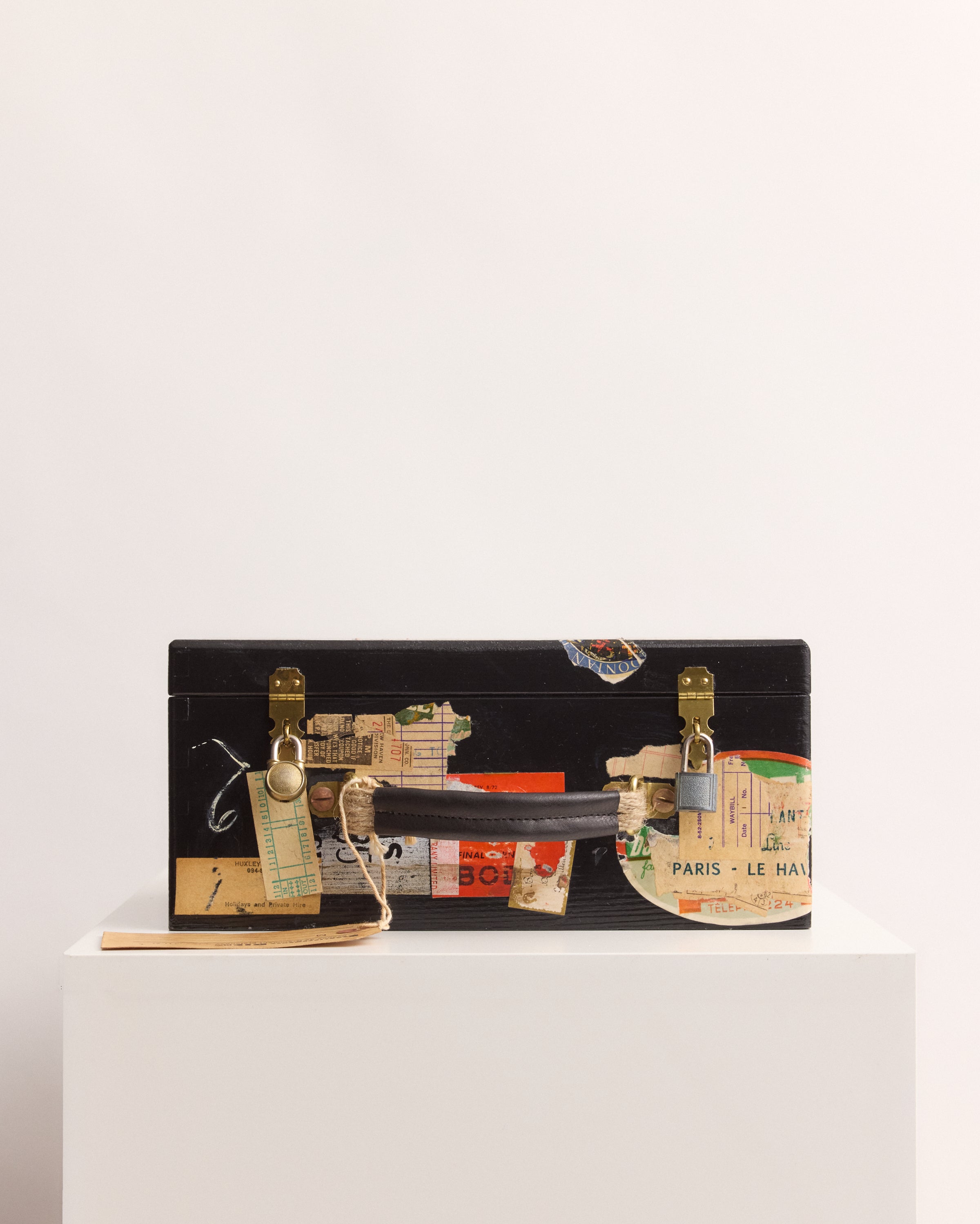 Black suitcase with travel-themed stickers on a white background