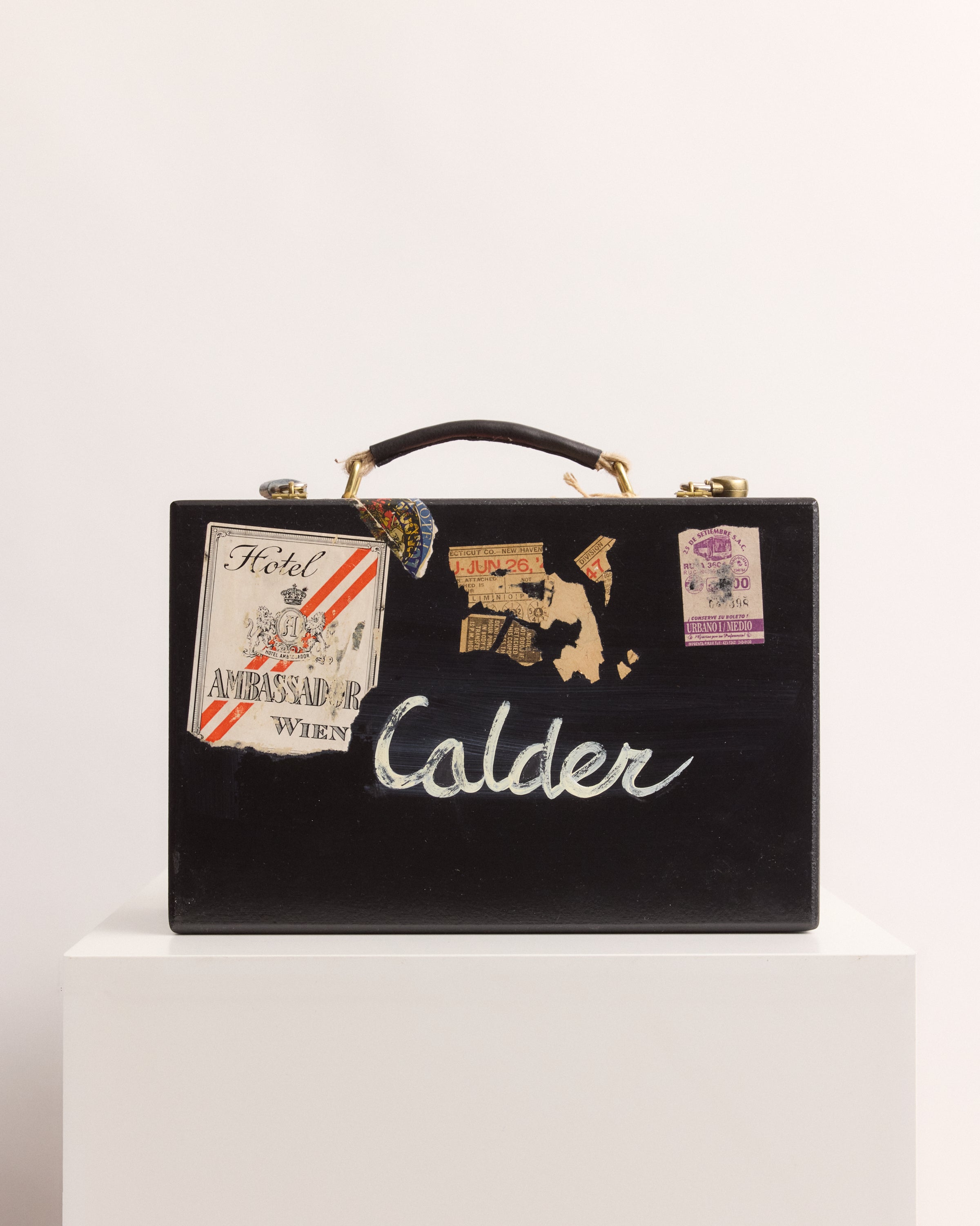 Black suitcase with 'Calder' branding and travel-themed stickers on a white background