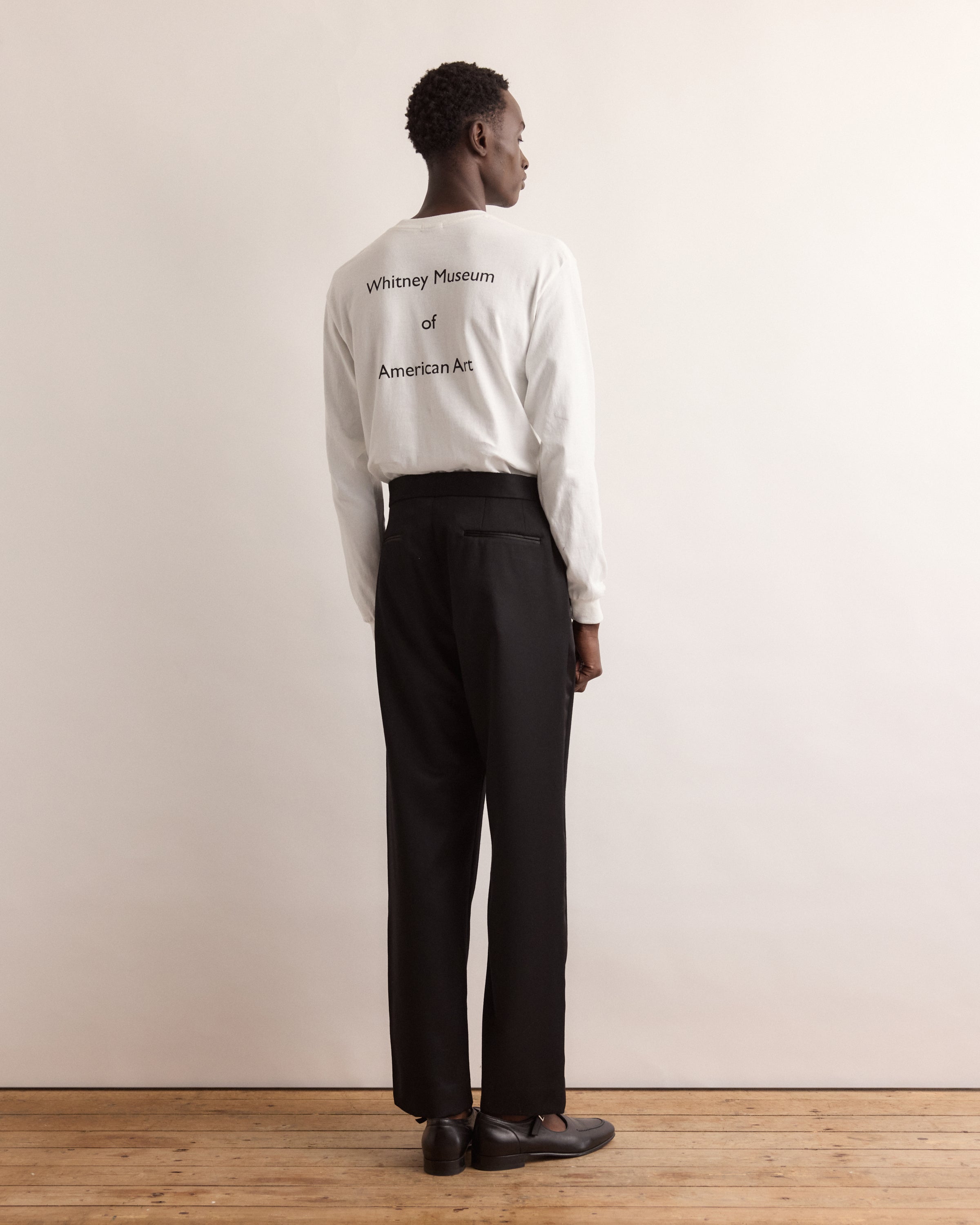 Person wearing a white sweatshirt with text, standing against a plain background