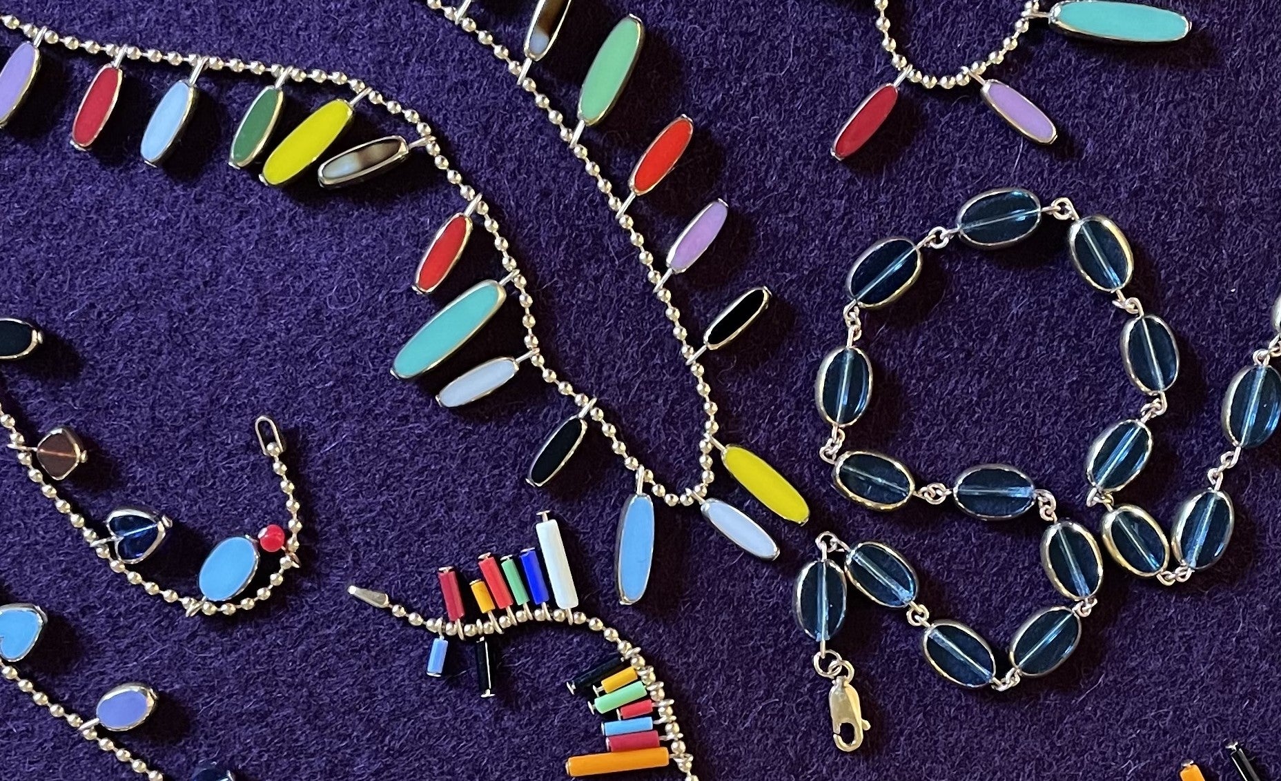 Assortment of glass beaded necklaces on a dark purple background