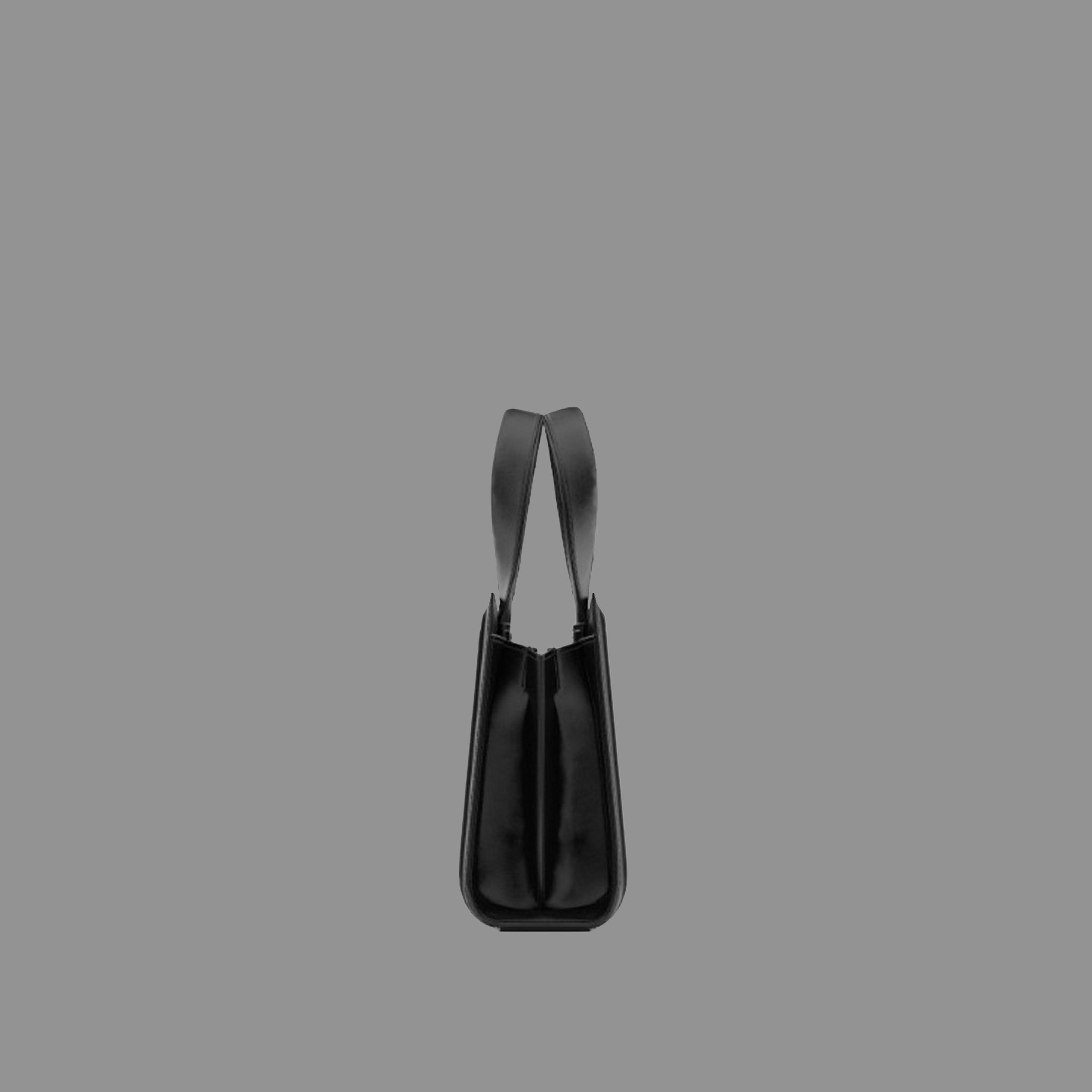 Side view of black leather handbag with thin straps on a gray background